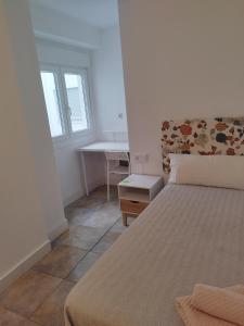 1 dormitorio con cama, mesa y ventana en Ecorooms SCQ estación, en Santiago de Compostela