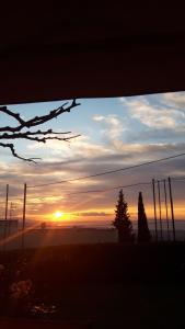 einen Sonnenuntergang über einem Feld mit Bäumen im Vordergrund in der Unterkunft Σπίτι με θέα in Nafpaktos