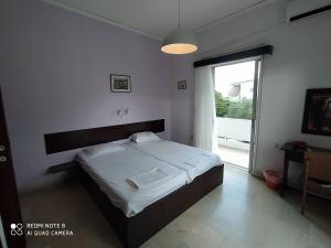 ein Schlafzimmer mit einem Bett und einem großen Fenster in der Unterkunft Dimitropoulos Apartments in Eleonas