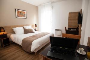 um quarto com uma cama e um computador portátil numa secretária em Apparthotel Privilodges Lyon Lumière em Lyon