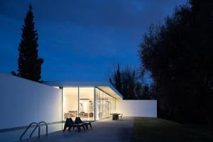 a house with two chairs sitting on a patio at night at Casa Briteiros in Guimarães