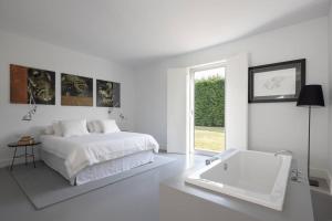 a white bedroom with a bed and a bath tub at Casa Briteiros in Guimarães