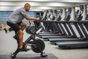 een man op een hometrainer in een sportschool bij voco Fiorello - LaGuardia East, an IHG Hotel in Queens