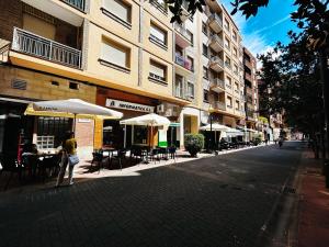 Una donna che cammina per una strada con tavoli e ombrelloni di Gran Via Centro a Logroño