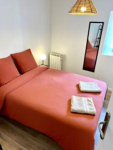 - une chambre avec un grand lit orange et 2 serviettes dans l'établissement « Petit Paris » - T2 centre ville Parking/balcon, à Albertville