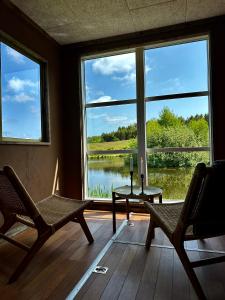 een kamer met 2 stoelen, een tafel en een groot raam bij Krusmølle Glamping in Aabenraa