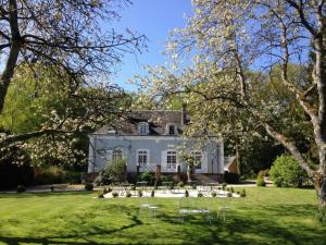 une maison blanche avec une pelouse et des arbres dans l'établissement Hôtel les Grands Chênes, à Saint-Fargeau