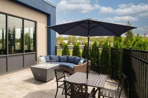 een patio met een bank, een tafel en een parasol bij Hampton Inn Seekonk in Seekonk