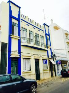 um edifício azul e branco com um carro estacionado em frente em Guest House Sao Filipe em Faro