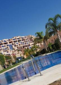 uma grande piscina com palmeiras e edifícios em Sea view cozy apartment La Tanita em Mojácar