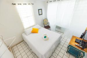 un pequeño dormitorio con una cama blanca con un osito de peluche. en Vieques Tropical Guest House, en Vieques