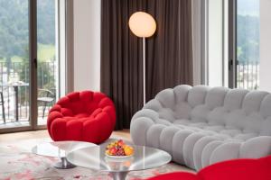 sala de estar con sofá blanco y silla roja en Swiss Hotel Apartments - Engelberg, en Engelberg