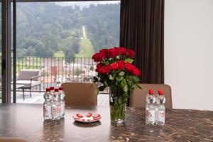 une table avec un vase de roses rouges et des bouteilles de soda dans l'établissement Swiss Hotel Apartments - Engelberg, à Engelberg