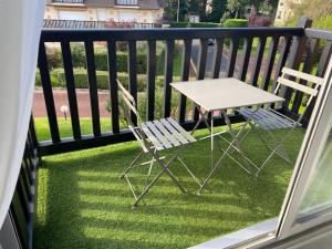 een tafel en 2 stoelen op een balkon bij Picsine, Tennis résidence sévigné 300m mer in Deauville