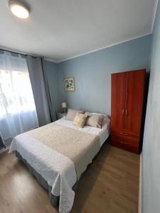 een slaapkamer met een bed en een houten kast bij Hostal Ravello in Viña del Mar