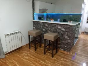 a kitchen with two stools and a fish tank at Apartman Una in Čačak