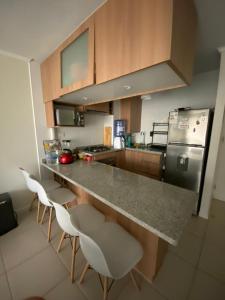 a kitchen with a counter with two chairs and a refrigerator at Depto hermoso El Tabo in El Tabo