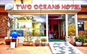 a two oceans hotel with potted plants in front of it at Two Oceans Hotel Voi in Voi