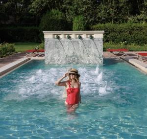 una donna in piedi in acqua in una piscina di QC Termeroma Spa and Resort a Fiumicino