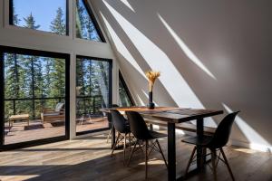 ein Esszimmer mit einem Tisch und Stühlen sowie großen Fenstern in der Unterkunft New Modern Rustic A-Frame Cabin with Barrel Sauna in Nordegg