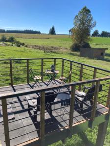 una terrazza in legno con sedie e un tavolo su un campo di Au p'tit cachot (Gîte insolite) a Vaux-sur-Sûre