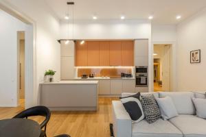 a living room with a couch and a kitchen at Luxurious Minimalist Residence with Sauna by Prestige Homes in Budapest