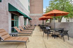 una fila de sillas y mesas con sombrillas en un patio en Embassy Suites Little Rock, en Little Rock