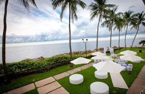 a patio with white tables and chairs and palm trees at The Condado Plaza Hotel in San Juan