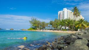 a person swimming in the water near a beach at The Condado Plaza Hotel in San Juan