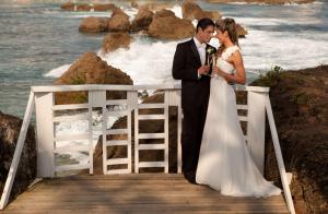 a bride and groom standing on a boardwalk by the ocean at The Condado Plaza Hotel in San Juan