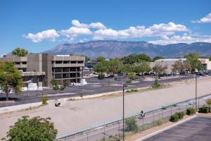 a parking lot with a building and mountains in the background at Hampton Inn Albuquerque - University/Midtown in Albuquerque