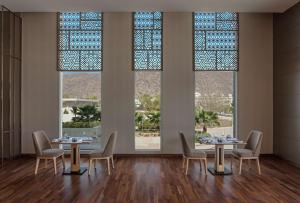 a dining room with two tables and chairs and windows at DoubleTree By Hilton Jaipur Amer in Jaipur