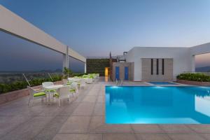 a pool on the roof of a building with tables and chairs at DoubleTree By Hilton Jaipur Amer in Jaipur