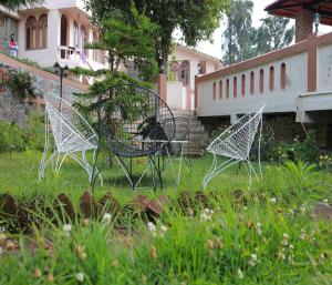 trois chaises assises dans l'herbe dans une cour dans l'établissement Mango Hill Kodai, à Kodaikānāl