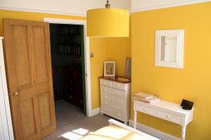 a yellow room with a dresser and a mirror at Charming 1800s Port Sunlight Worker's Cottage in Port Sunlight