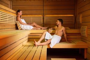 un uomo e una donna seduti in una sauna di Hilton Rijeka Costabella Beach Resort And Spa a Fiume (Rijeka)