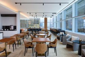 un restaurante con mesas, sillas y ventanas grandes en JW Marriott Dallas Arts District, en Dallas