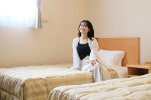 een vrouw op een bed in een hotelkamer bij Hotel Pony Onsen in Towada