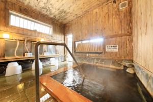 een badkamer met een bad met water erin bij Hotel Pony Onsen in Towada