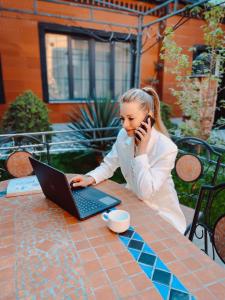 una donna seduta a un tavolo con un portatile e un cellulare di Aspar Boutique Hotel a Yerevan