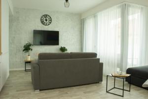 uma sala de estar com um sofá e um relógio na parede em Apartmán X28 em Mikulov