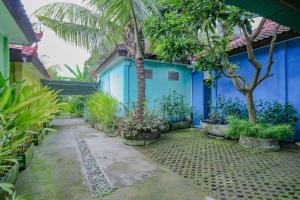 un bâtiment bleu avec des arbres et des plantes devant lui dans l'établissement OYO Life 90301 Hidden Village Uluwatu, à Jimbaran