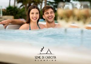 un hombre y una mujer en un jacuzzi en I Sicomori - Seme di Carota - Glamping e appartamenti con piscina a Saturnia, en Saturnia