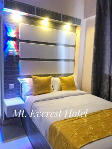 a bed with yellow pillows in front of a window at Mt. Everest Hotel in Kisii