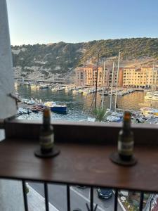 una ventana con vistas al puerto y 2 botellas de cerveza en Appartement vue sur le port - Chez Carlu, en Bonifacio