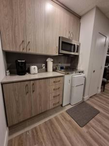 een keuken met houten kasten en witte apparaten bij Cozy Sweet Studio #9. Ten min to D.T Ottawa in Gatineau