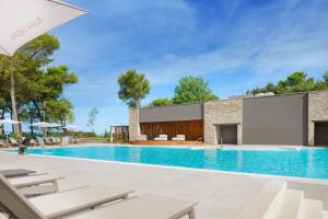 einen Pool mit Stühlen und ein Gebäude in der Unterkunft Istrian Villas Plava Laguna in Umag