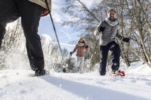 dwoje ludzi spacerujących po śniegu z psem w obiekcie Belambra Clubs Praz-sur-Arly - L'Alisier w mieście Praz-sur-Arly