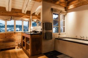 een badkamer met een bad, een wastafel en ramen bij Zannier Le Chalet in Megève