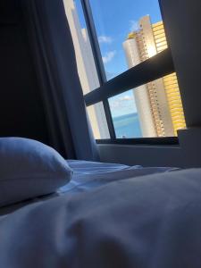 um quarto com uma cama e uma janela com edifícios em Ilusion Hotel Ponta Negra em Natal